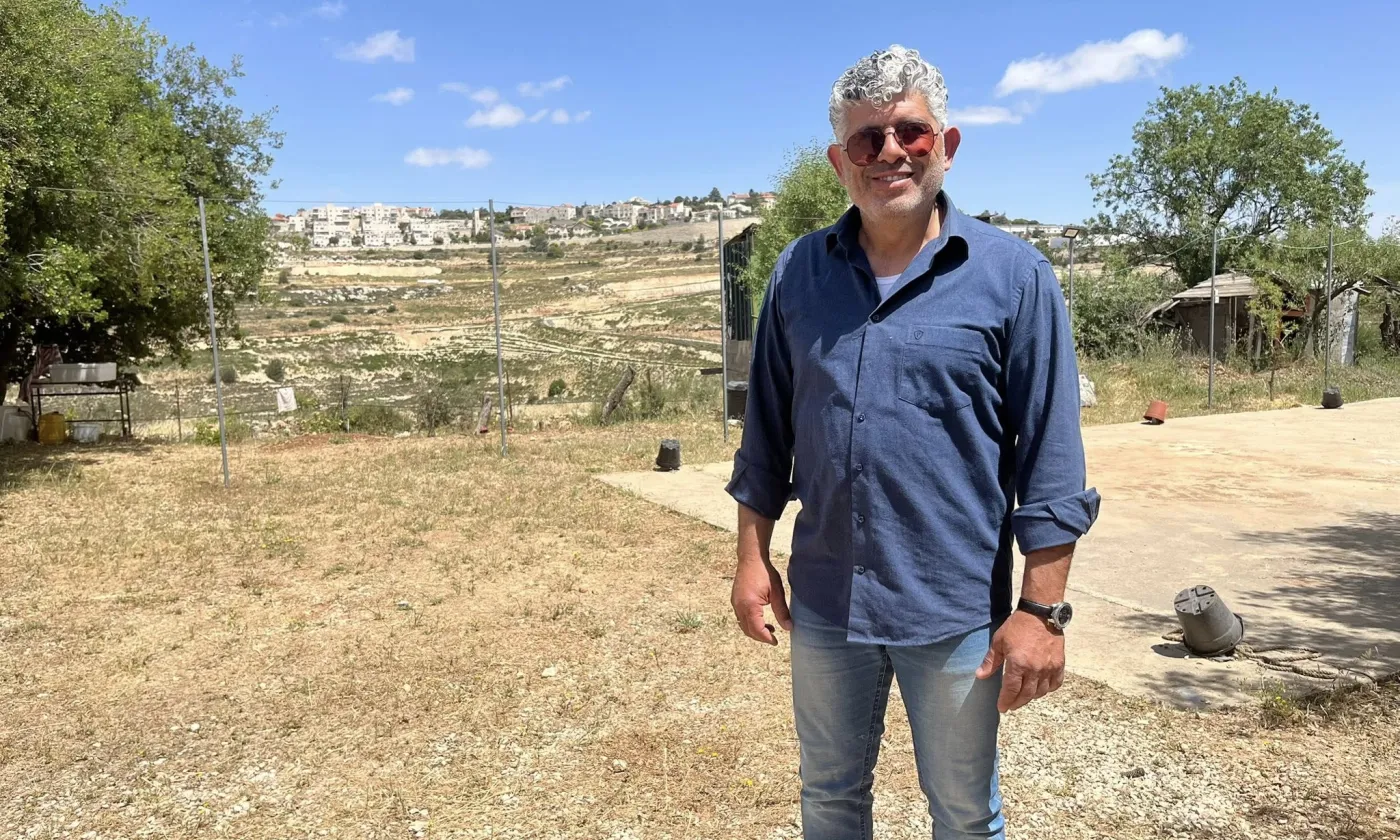 Daoud Nassar dans son exploitation, à une dizaine de kilomètres de Bethléem, en mai. Derrière lui, au fond, la colonie israélienne de Neve Daniel. © Amira Souilem