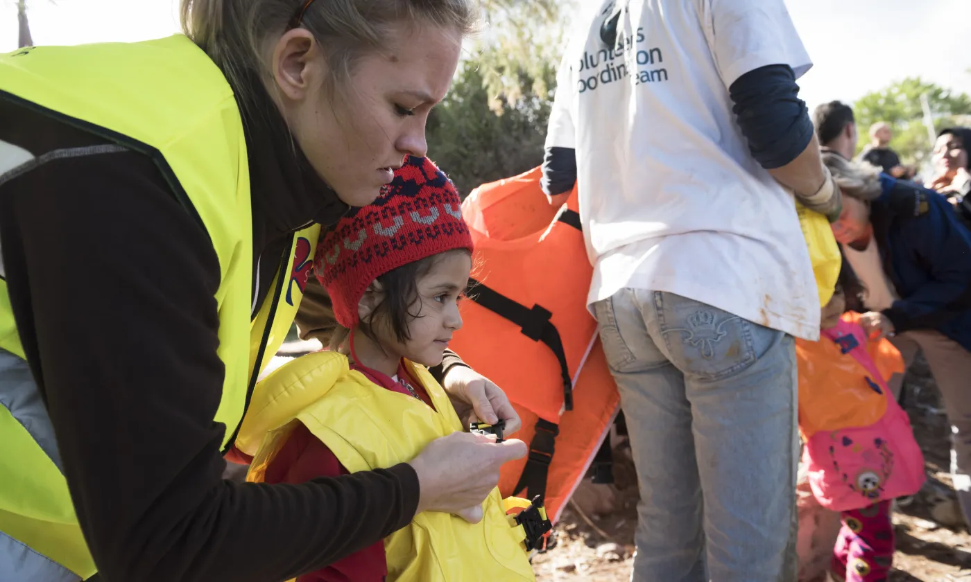 Octobre 2015, Lesbos: une bénévole norvégienne aide une petite fille à retirer son gilet de sauvetage après qu'elle a parcouru 10 kilomètres en haute mer sur un canot de fortune. IStock