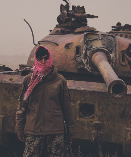 Août 2021, dans un faubourg de Kaboul (Afghanistan), un homme armé pose devant une épave de tank taliban. / ©iStock/Trent Inness