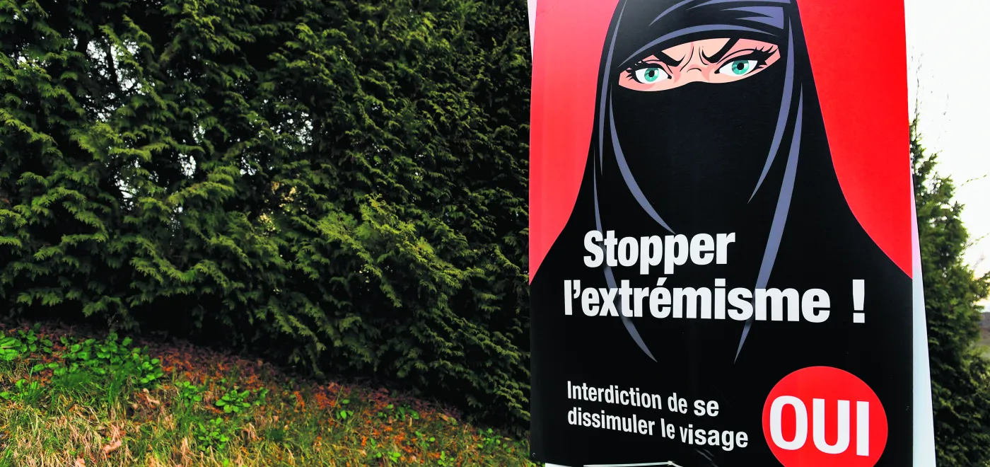 Vevey, le 7 mars 2021. Une affiche en faveur de l’interdiction de se dissimuler le visage acceptée par les électeurs suisses ce jour-là. Si le type de vêtements représentés est ultraminoritaire en Suisse, les promoteurs de l’initiative ont largement utilisé cette symbolique dans leur campagne. © Shutterstock