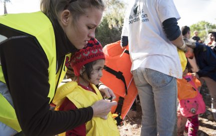 Octobre 2015, Lesbos: une bénévole norvégienne aide une petite fille à retirer son gilet de sauvetage après qu&#039;elle a parcouru 10 kilomètres en haute mer sur un canot de fortune. / IStock