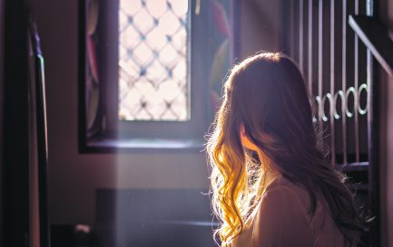 Jeune adolescente regardant par la vitre d&#039;une église. / © iStock